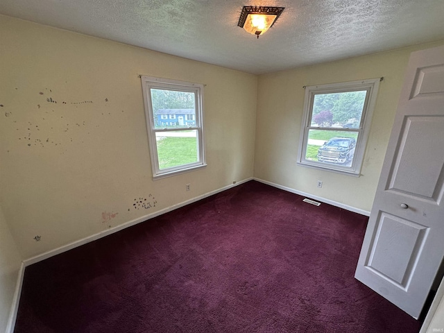 empty room featuring baseboards, dark colored carpet, and a textured ceiling