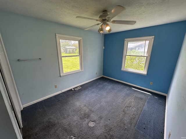 spare room with ceiling fan, dark colored carpet, a textured ceiling, and baseboards