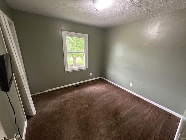 unfurnished room featuring a textured ceiling, dark carpet, and baseboards