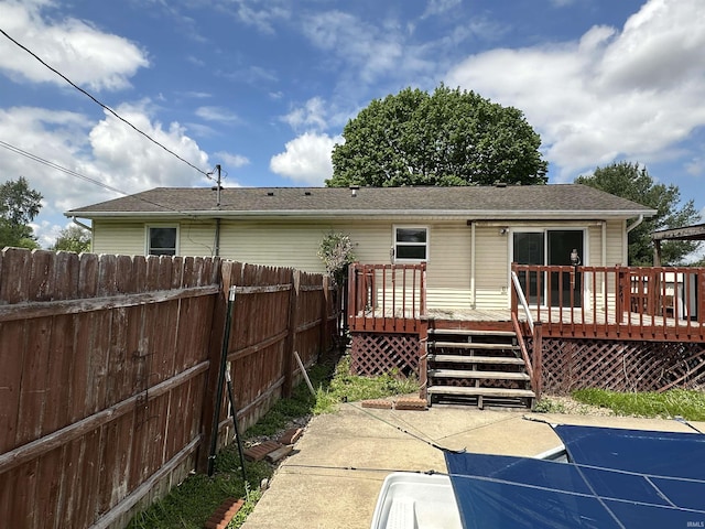 back of property featuring fence, a wooden deck, and roof with shingles
