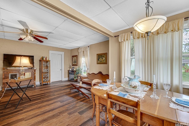 dining area featuring wood finished floors, healthy amount of natural light, a ceiling fan, a paneled ceiling, and baseboards