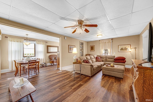 living area with a drop ceiling, baseboards, wood finished floors, a ceiling fan, and healthy amount of natural light