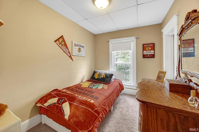 bedroom with carpet, a paneled ceiling, and baseboards