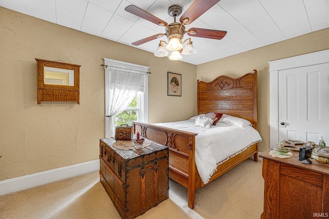 bedroom with light colored carpet, ceiling fan, baseboards, and a textured wall