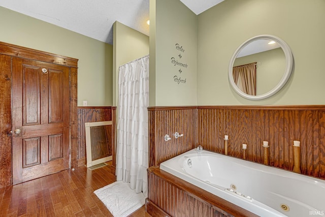 full bathroom with wainscoting, a whirlpool tub, and wood finished floors