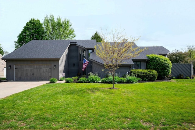 mid-century home featuring an attached garage, a front lawn, concrete driveway, roof with shingles, and a chimney