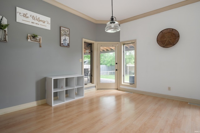 doorway with ornamental molding, wood finished floors, and baseboards