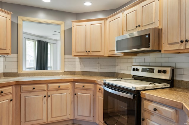 kitchen with stainless steel microwave, range with electric stovetop, light brown cabinetry, decorative backsplash, and recessed lighting
