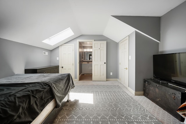 carpeted bedroom featuring a skylight, vaulted ceiling, baseboards, and connected bathroom