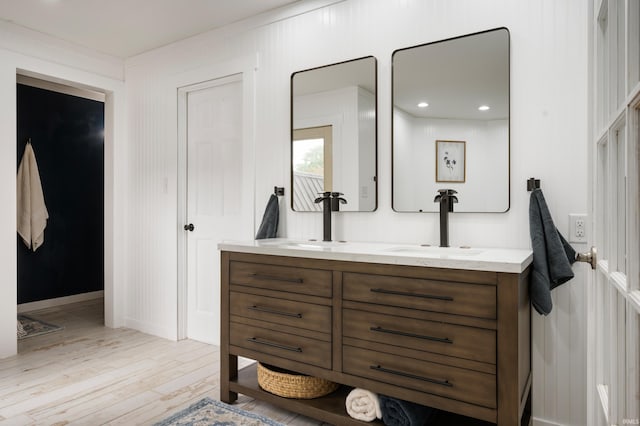 bathroom with wood finished floors, double vanity, and baseboards