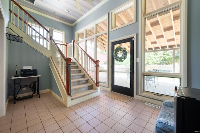 foyer entrance featuring tile patterned floors, stairs, crown molding, and baseboards