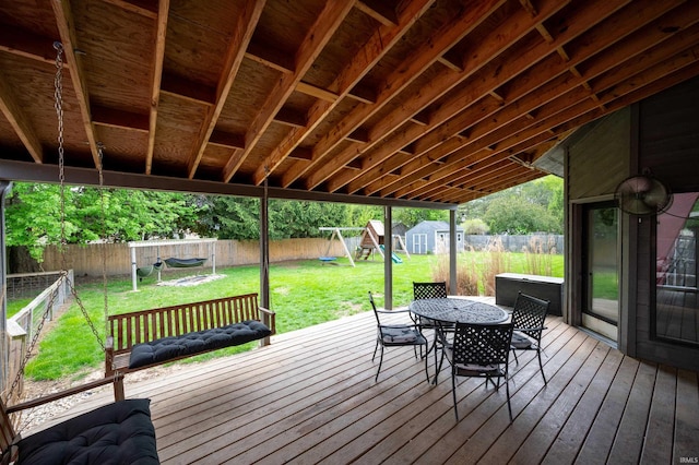 deck with a playground, a storage shed, outdoor dining space, and an outdoor structure