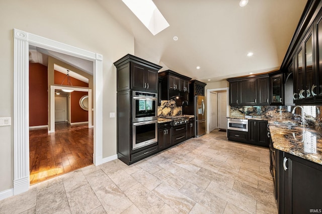 51167 Huntington Ln, Granger, IN 46530 - kitchen with appliances with stainless steel finishes, vaulted ceiling, a sink, backsplash, and a skylight