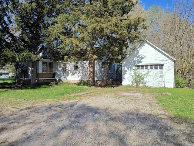 obstructed view of property with a detached garage, a front yard, and driveway