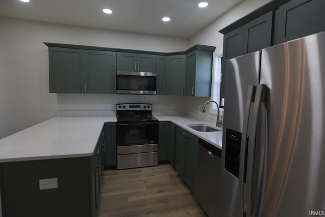 kitchen with stainless steel appliances, a sink, light wood-style flooring, recessed lighting, and light countertops