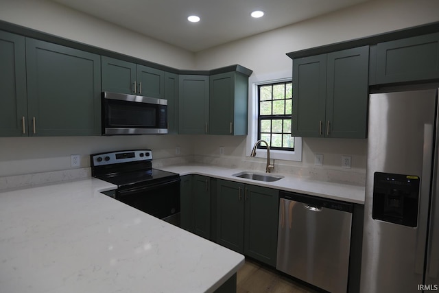 kitchen with appliances with stainless steel finishes, a sink, recessed lighting, dark wood-type flooring, and light stone countertops