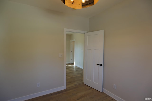 spare room with baseboards and wood finished floors