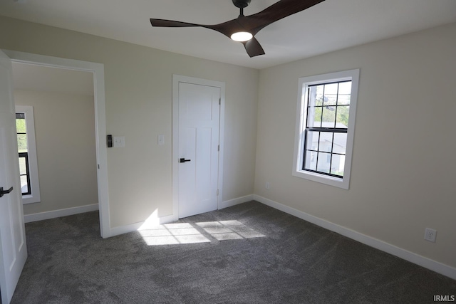 unfurnished bedroom with dark colored carpet, baseboards, and ceiling fan