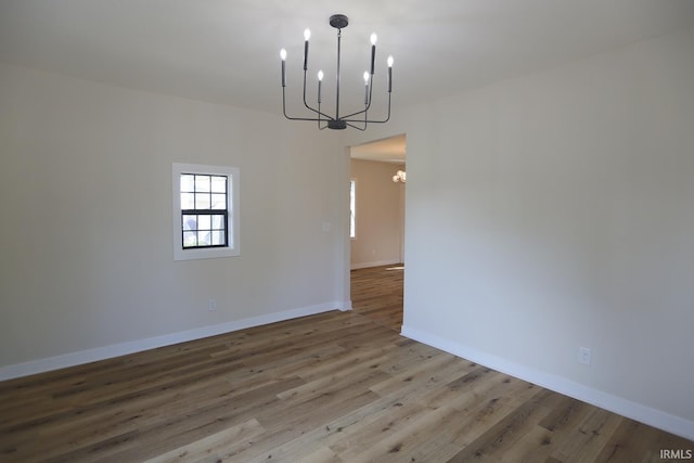unfurnished dining area featuring a chandelier, wood finished floors, and baseboards