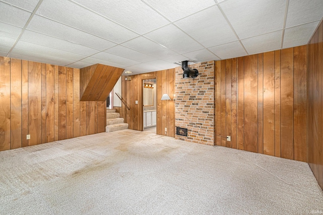 additional living space with wooden walls, carpet flooring, stairway, and a fireplace