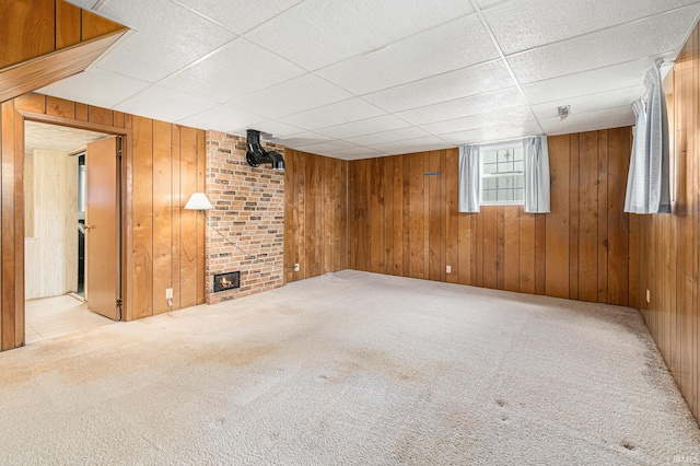 basement with carpet flooring, wooden walls, a fireplace, and a paneled ceiling