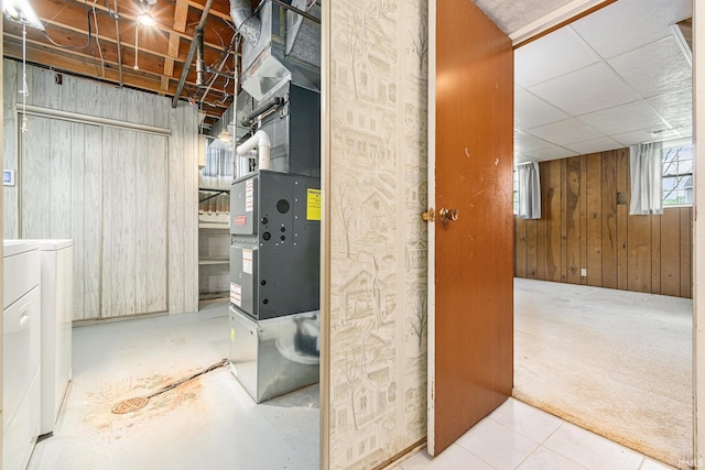 basement with washing machine and dryer, wood walls, and heating unit