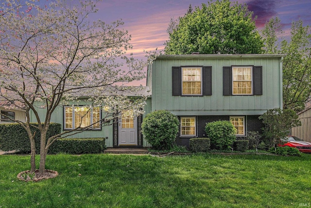 split level home featuring a front yard, board and batten siding, and brick siding