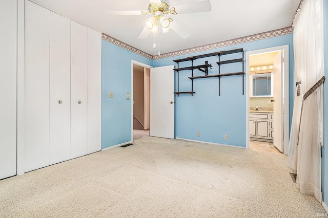 unfurnished bedroom with light carpet, baseboards, ensuite bathroom, and a ceiling fan