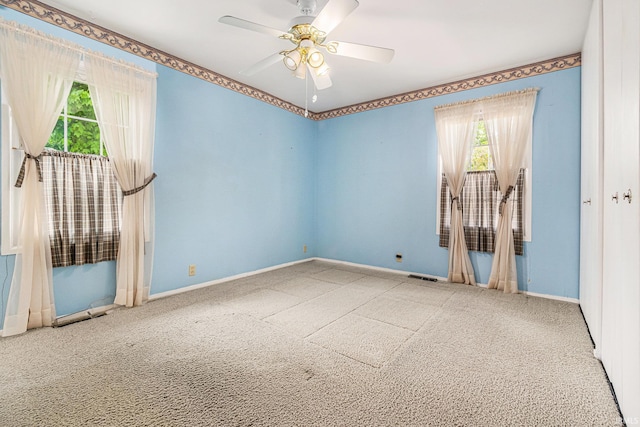 carpeted empty room with baseboards and a ceiling fan