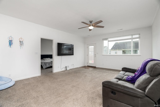 carpeted living room featuring ceiling fan and baseboards