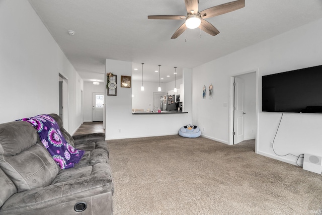 carpeted living area with ceiling fan and baseboards