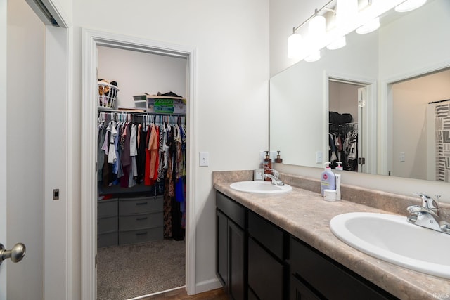full bathroom with double vanity, a spacious closet, and wood finished floors