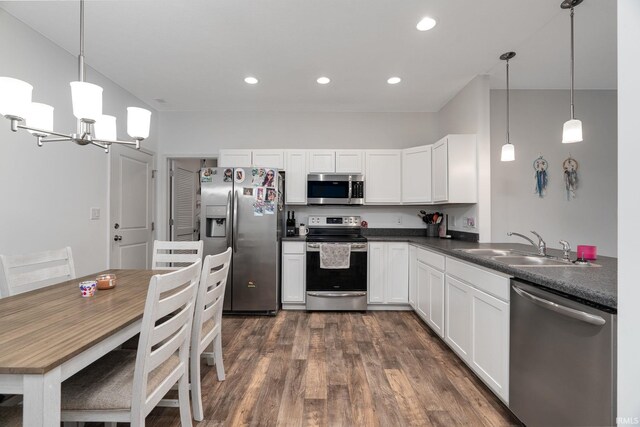 kitchen featuring appliances with stainless steel finishes, a sink, dark countertops, dark wood-style flooring, and white cabinets