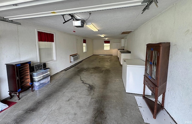 garage with washer and clothes dryer, a garage door opener, refrigerator, and a textured wall