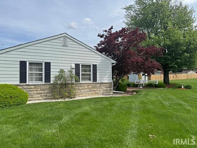 view of property exterior featuring stone siding and a lawn