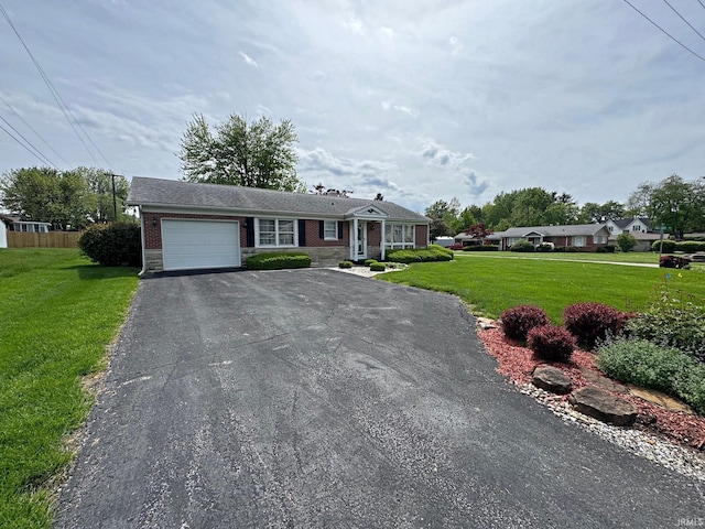 view of front of home featuring an attached garage, a front lawn, driveway, and brick siding