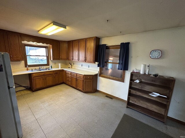 15850-2 Witt Rd, Shoals, IN 47581 - kitchen featuring freestanding refrigerator, a sink, baseboards, light countertops, and brown cabinetry