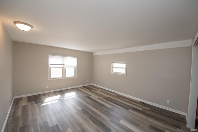 empty room featuring baseboards and dark wood-type flooring