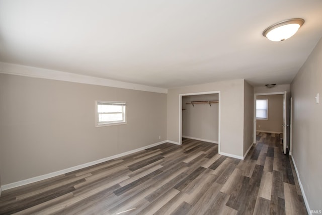 unfurnished bedroom featuring dark wood-style floors, a closet, and baseboards