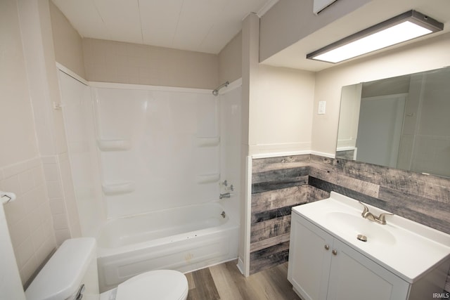bathroom featuring toilet, wood finished floors,  shower combination, and vanity