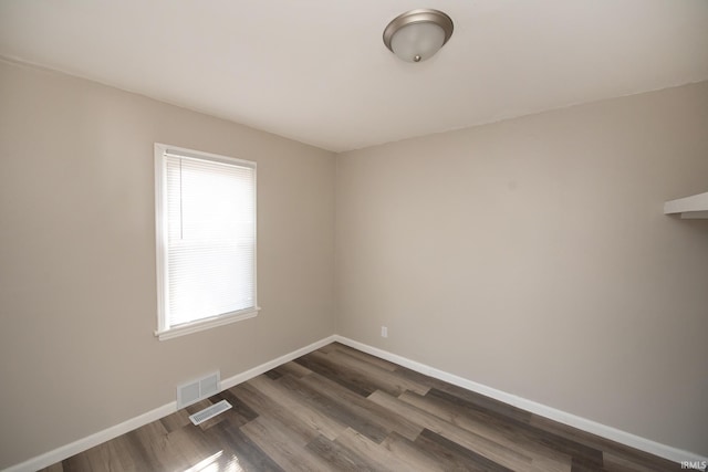 unfurnished room featuring baseboards and dark wood-type flooring