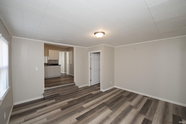 unfurnished living room featuring dark wood-style floors, baseboards, and crown molding