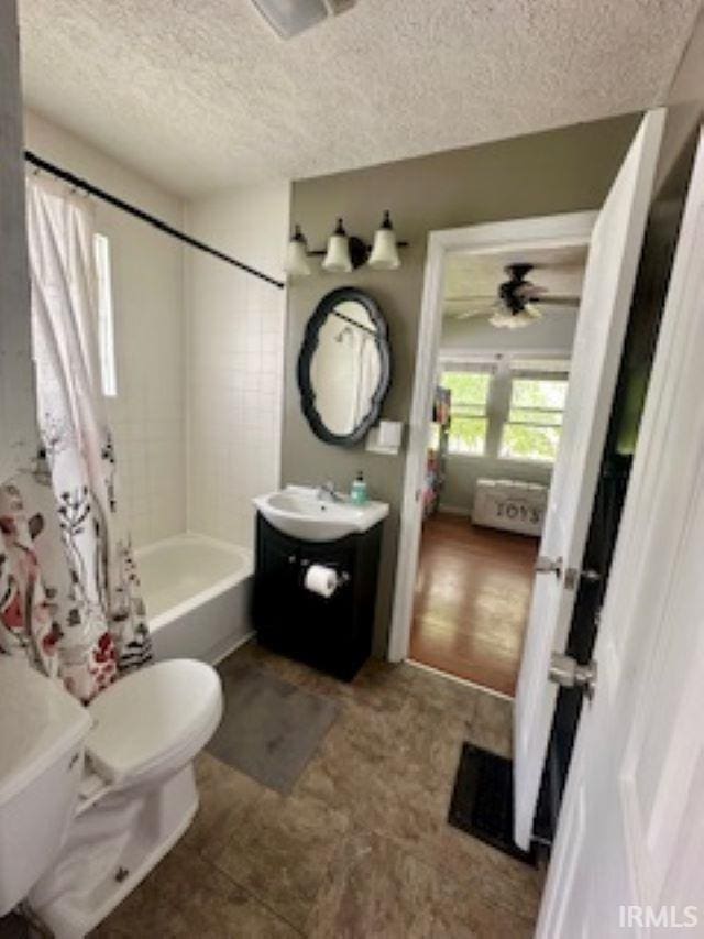 bathroom featuring a textured ceiling, toilet, vanity, shower / bathtub combination with curtain, and ceiling fan