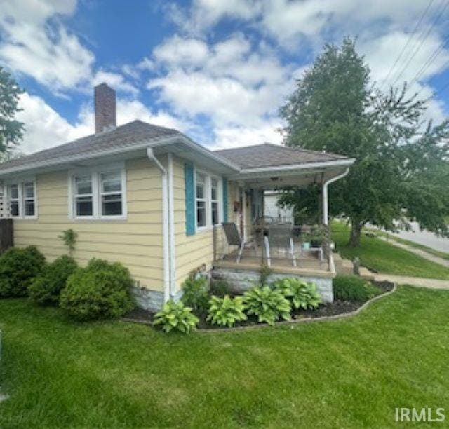 view of side of home featuring a chimney and a yard