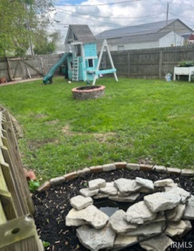 view of yard featuring a playground, an outdoor fire pit, an outdoor structure, and a storage unit