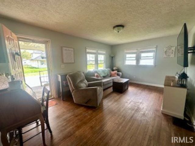 living room featuring a textured ceiling, wood finished floors, and baseboards