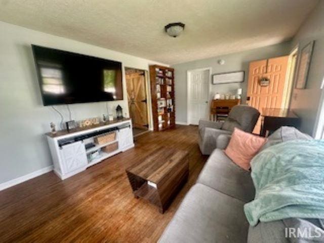 living room with dark wood-style floors, baseboards, and a wall mounted air conditioner