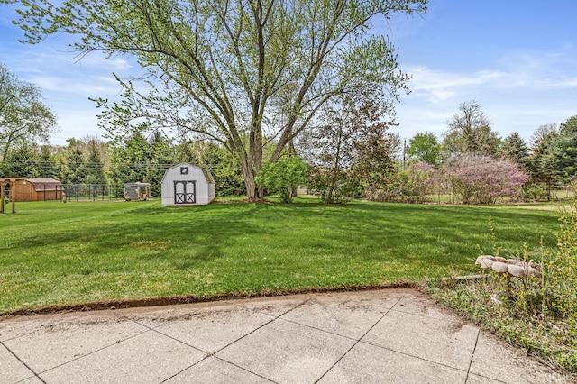 view of grassy yard with a storage unit, an outbuilding, and a patio area