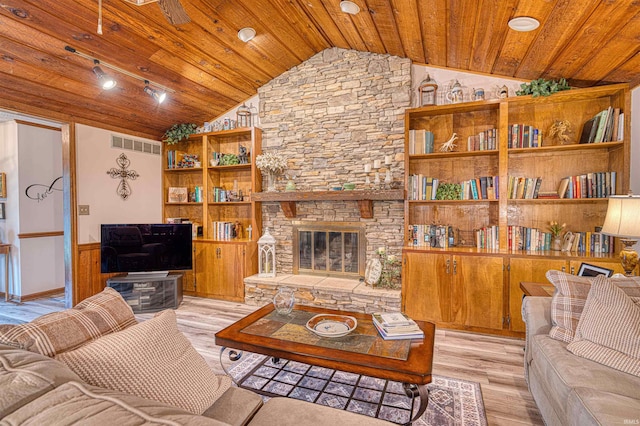 living room with wood ceiling, lofted ceiling, light wood finished floors, and a stone fireplace