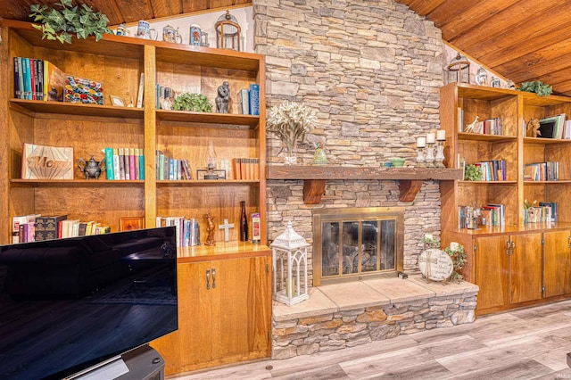 living room with wood ceiling, vaulted ceiling, light wood finished floors, and a stone fireplace